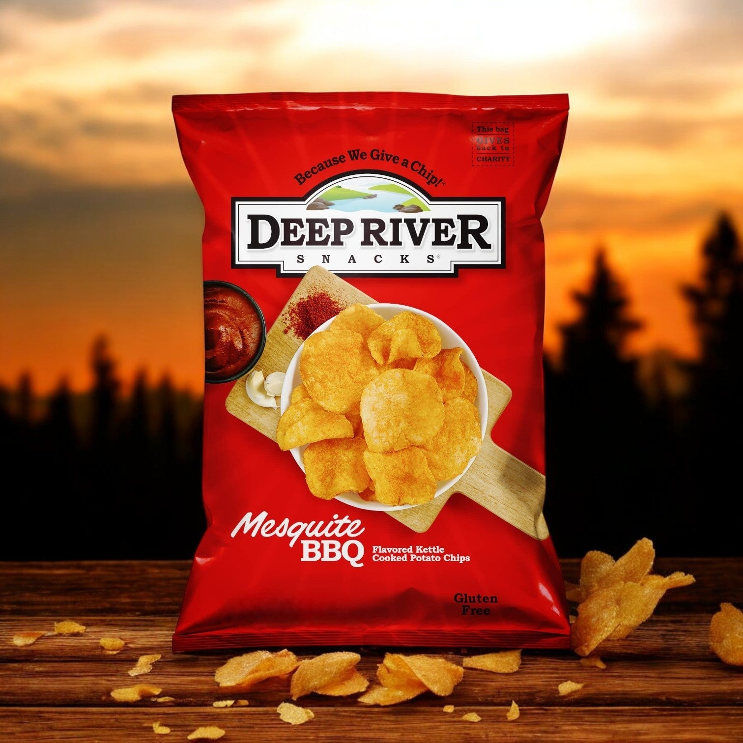 Deep River Snacks Mesquite BBQ Kettle Potato Chips, 1.375 oz., scattered amidst a sunset forest backdrop, offers smoky, gluten-free enjoyment from non-GMO potatoes. Available in 48 per case.