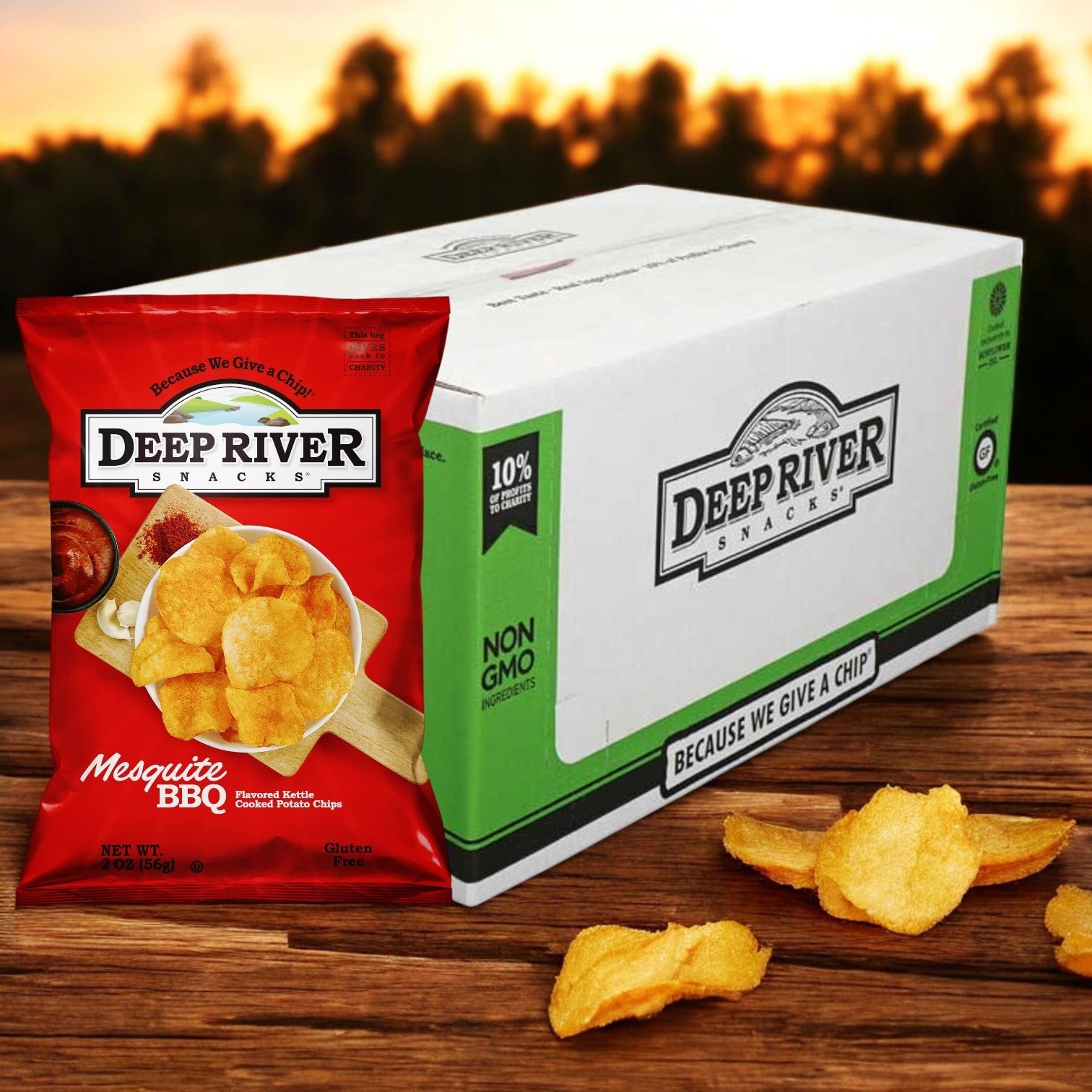 A 2-ounce bag of Deep River Snacks Mesquite BBQ Kettle Potato Chips from a 24-pack case rests beside a branded box on a wooden table, surrounded by scattered chips.