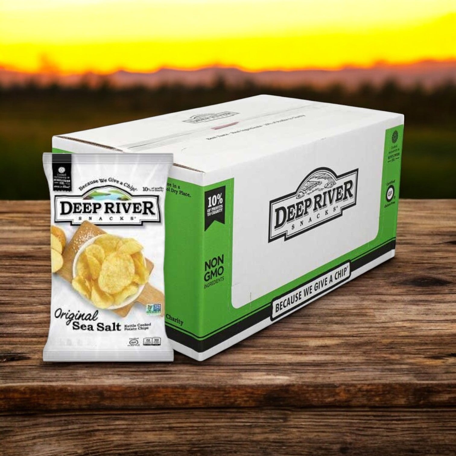 A 1-ounce bag of Deep River Snacks Original Sea Salt Kettle Potato Chips, featuring the brand's logo, sits before a larger box against a sunset backdrop. These chips are made with Non-GMO potatoes and provide a gluten-free snacking option.