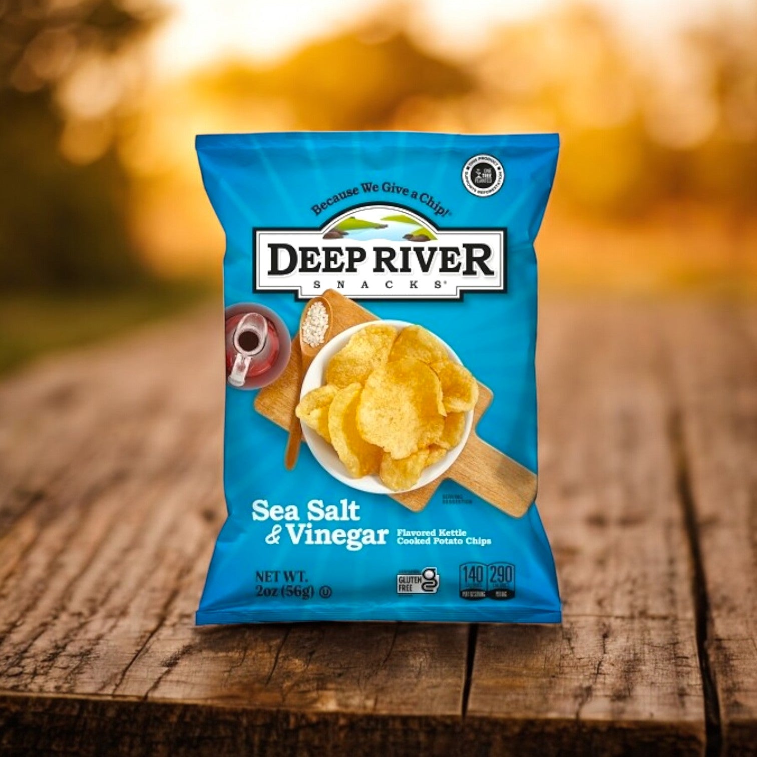 A bag of Deep River Snacks Salt & Vinegar Kettle Potato Chips, gluten-free and weighing 2 ounces, sits on a wooden surface.