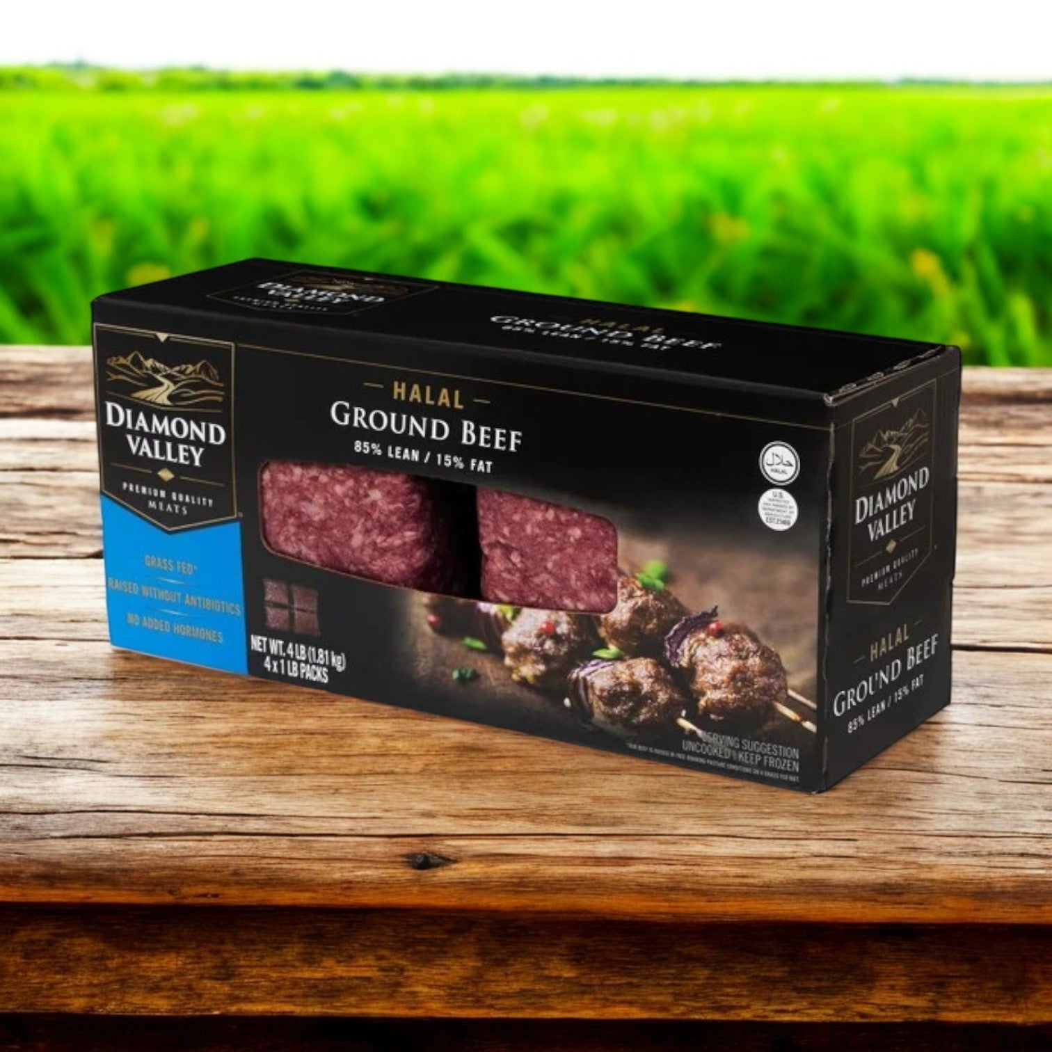 A box of Diamond Valley Halal Ground Beef, 85% lean, by New Zealand Spring Lamb rests on a wooden surface with a green field backdrop—perfect for pairing with premium tuna to craft exquisite seafood dishes.