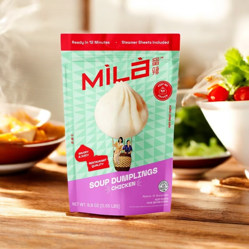 A MiLa Frozen Soup Dumpling - Chicken - 1 Count sits on a sunlit table with a bowl of greens and frozen dumplings in the background, showcasing Mila's savory broth and tender chicken for an exquisite dining experience.