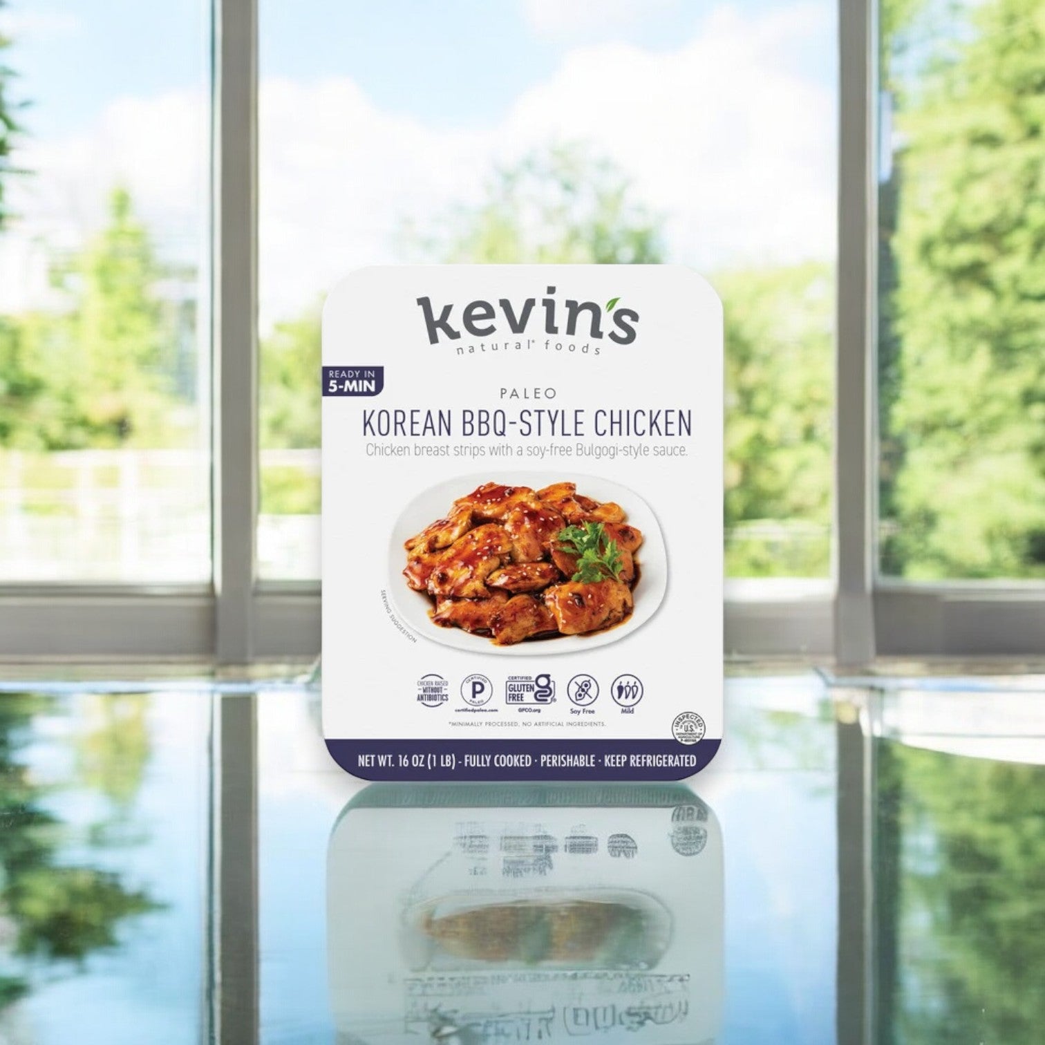 Kevin's Korean BBQ-Style Beef, 16 oz., from Kevin's is elegantly showcased on a reflective surface with lush greenery behind it. The authentic flavors transport you to Korea, captivating the senses and evoking culinary wanderlust. Ships frozen; keeps 30 days once thawed in the cooler!.