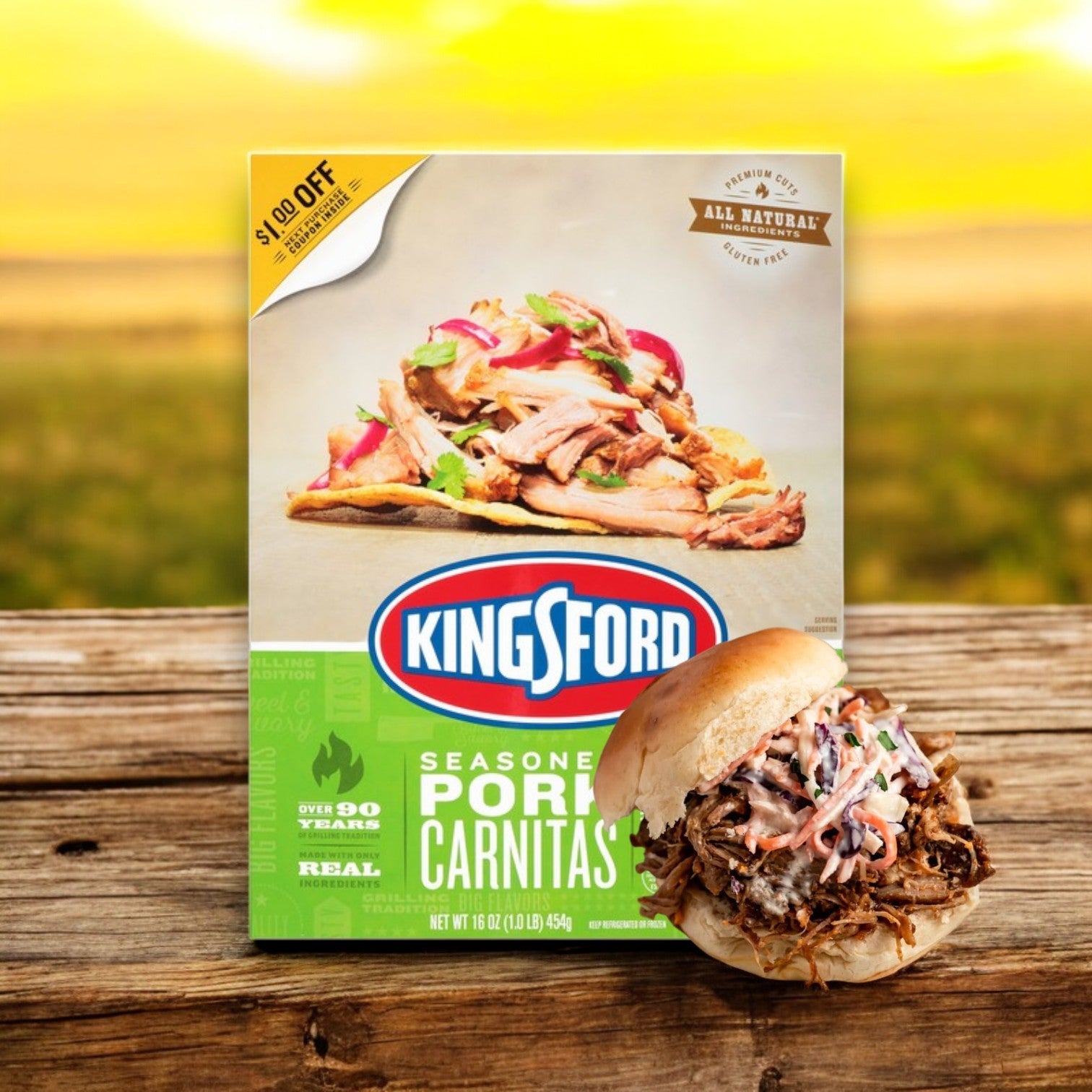 A box of Kingsford Seasoned Pork Carnitas – 16 oz with smoky seasoning and a discount label sits on rustic wood next to a pork sandwich, set against a blurred sunny landscape that promises authentic flavor in every bite.