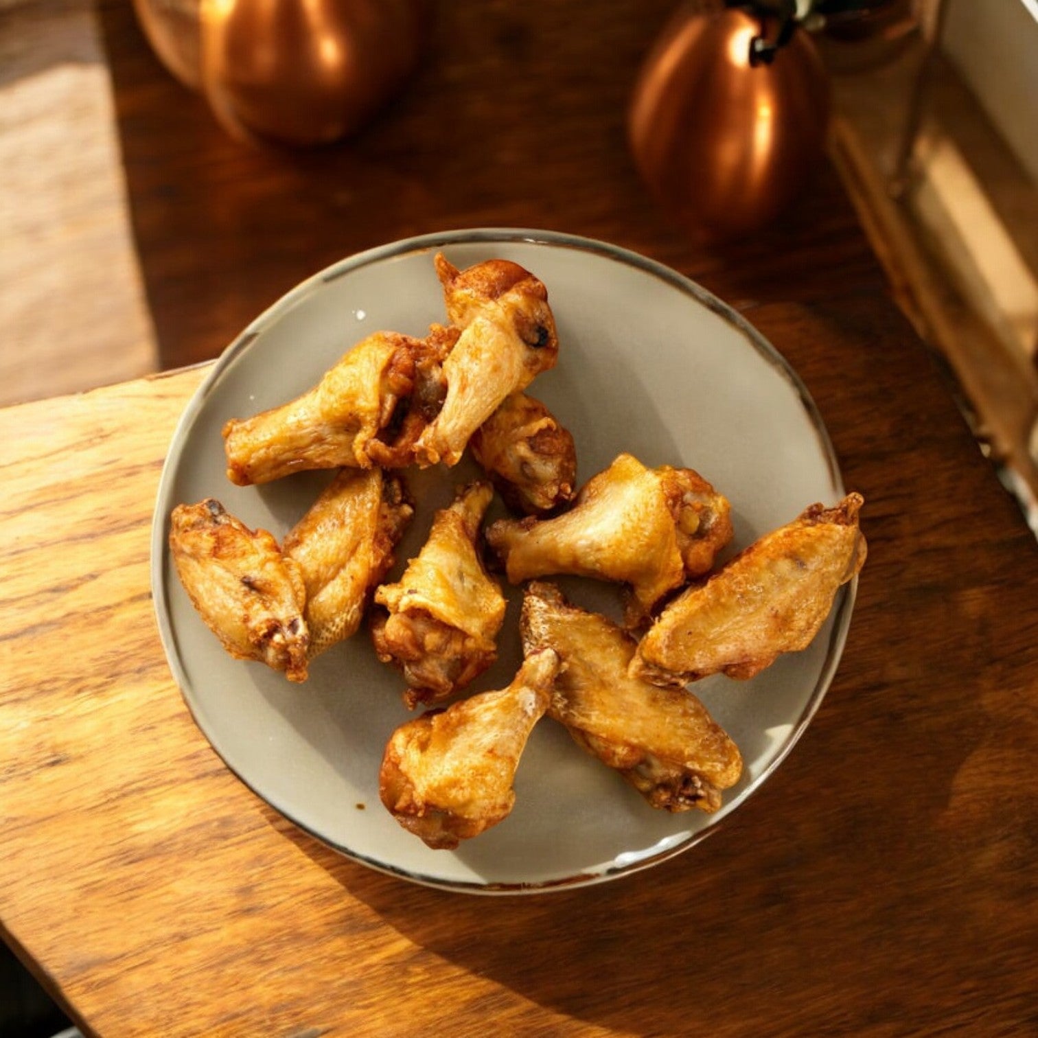 A plate of Kirkland Signature Chicken Wings, totaling 30 pounds across 3 bags, sits on a wooden table under soft lighting, highlighting their versatility and quality perfect for diverse cooking options.
