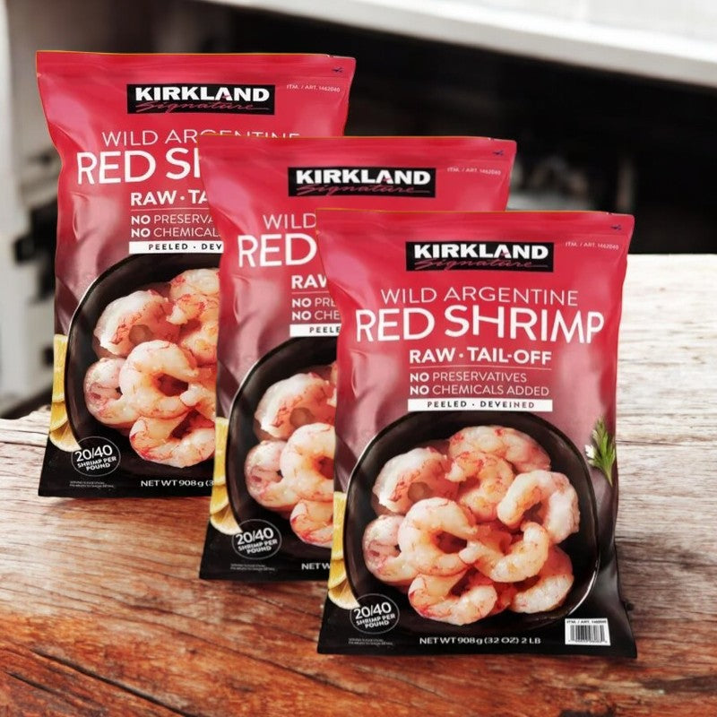 Three bags of Kirkland Signature Wild Argentine Raw Shrimp, totaling 6 lbs and known for their wild-caught quality and frozen freshness, are displayed on a wooden surface. Each 2 lb bag is raw, tail-off, with no preservatives or chemicals added.
