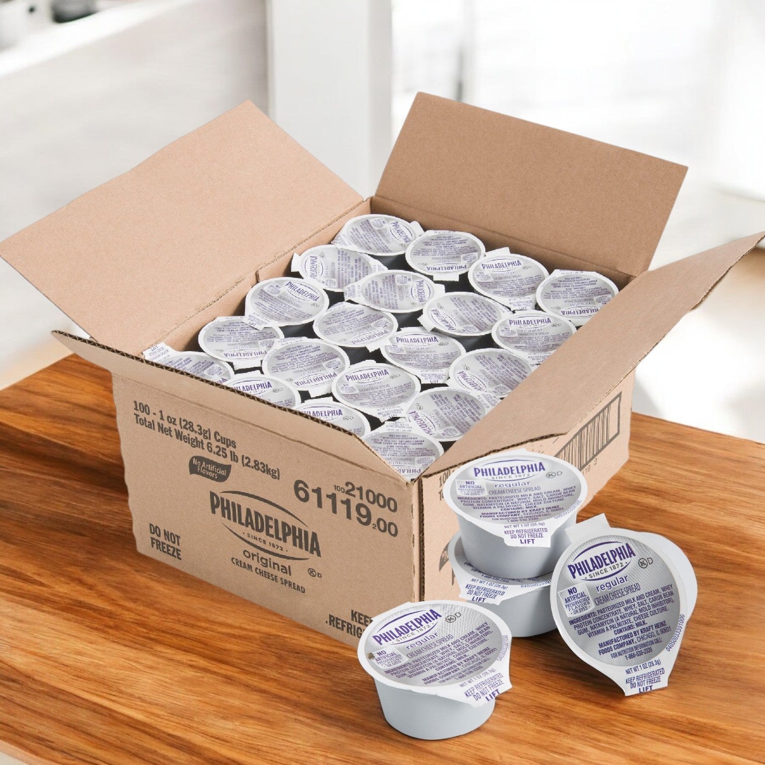 A box of Kraft's Philadelphia Cream Cheese Cheese Cream Original Spread sits on a wooden table, with several 1 oz. cups from the 100-count pack arranged invitingly in front.