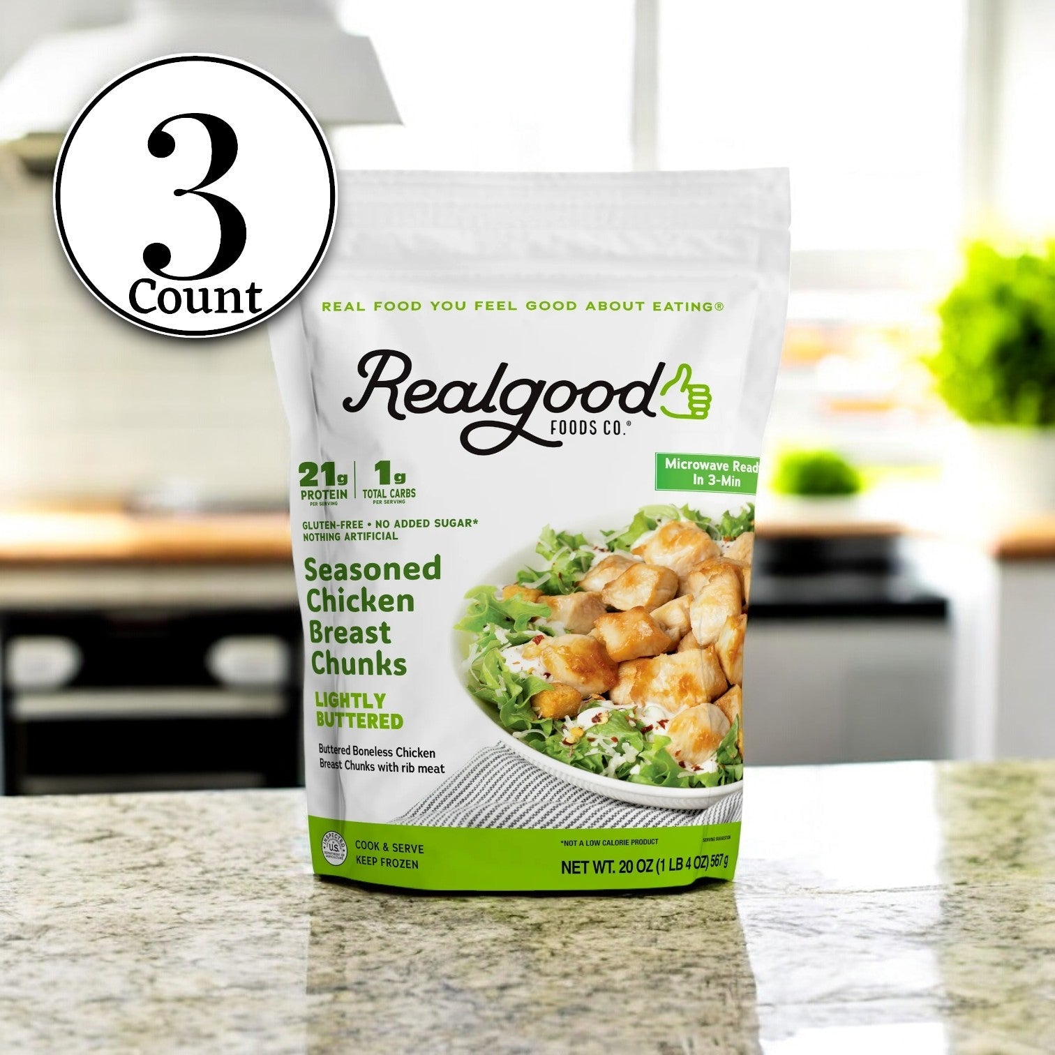 On the kitchen counter sits a bag of Real Good Foods' Lightly Buttered Chicken Breast Nuggets, featuring 23g protein, 1g net carbs, and a "3 Bag" emblem.