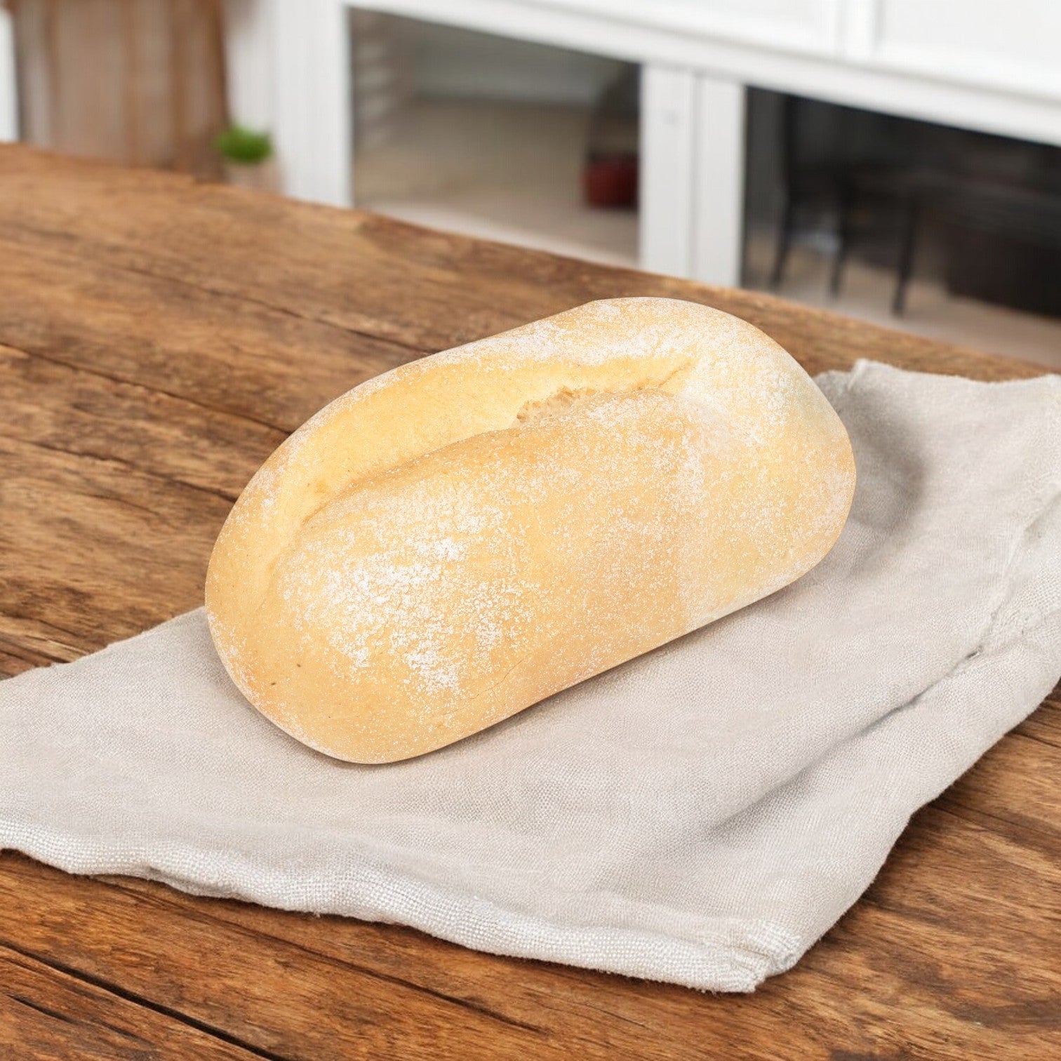 This Udi's Gluten Free French Dinner Roll, with its soft and fluffy texture, is comfortably placed on a beige cloth atop a wooden table.