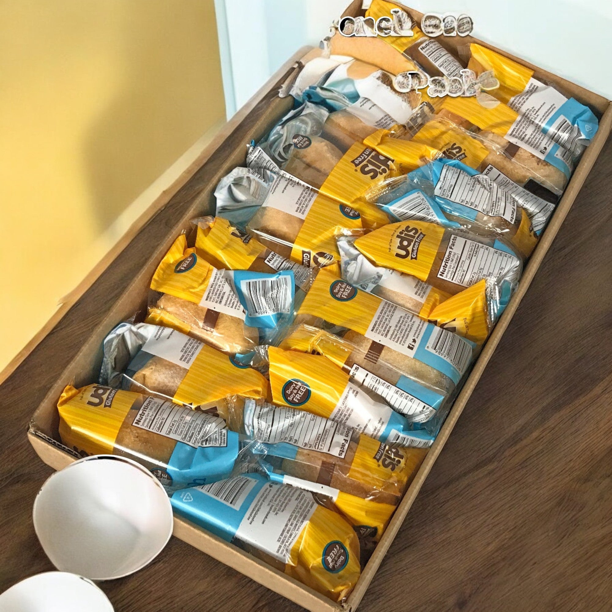 A box of individually wrapped, soft, and fluffy gluten-free rolls labeled "Udi's Roll Dinner French" sits on the table.