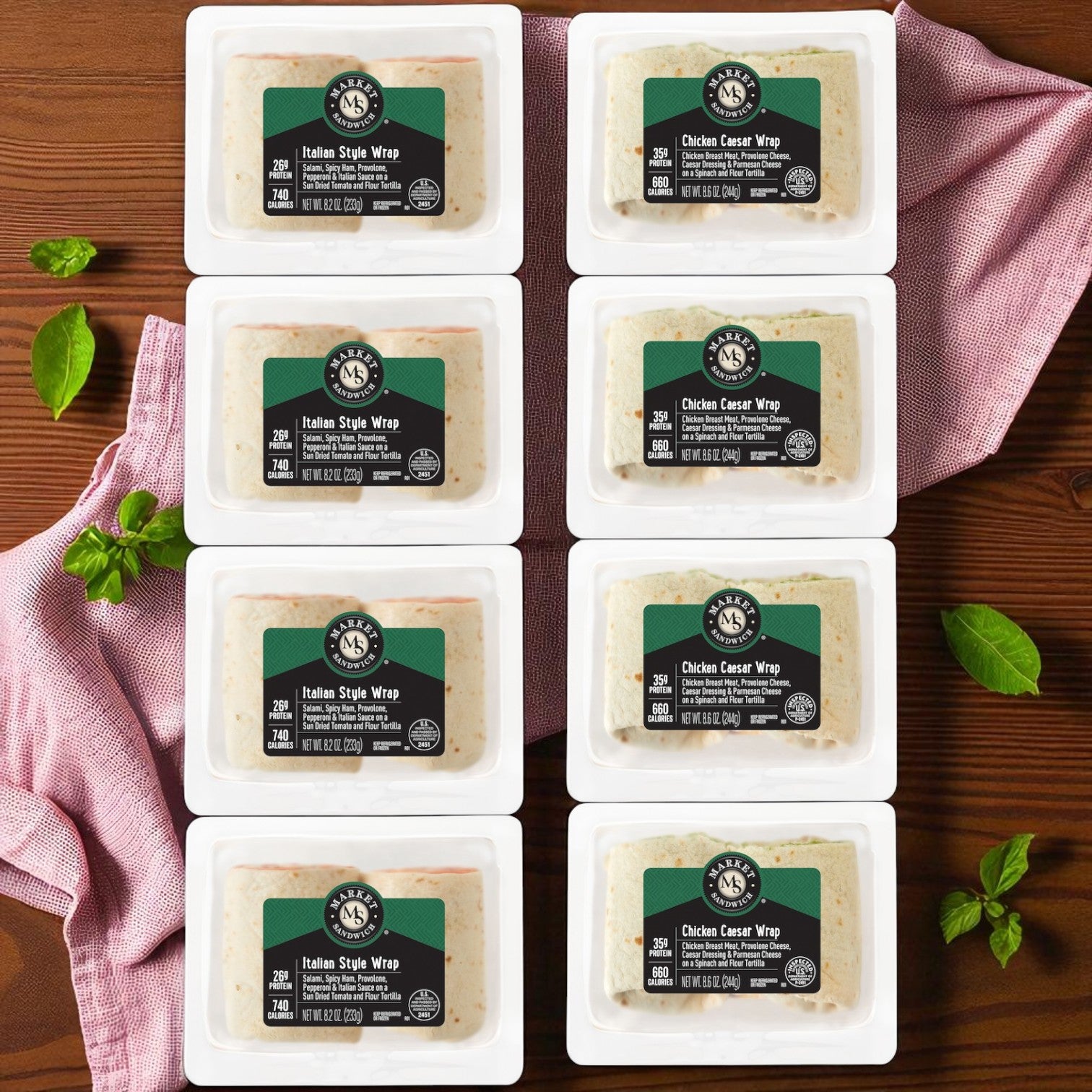 Eight E.A. Sween Market Wrap Combo Pack sandwiches—four Italian Style Wraps (8.2 oz) and four Chicken Caesar Wraps (8.6 oz)—are displayed on a wooden surface with a pink cloth and basil leaves.