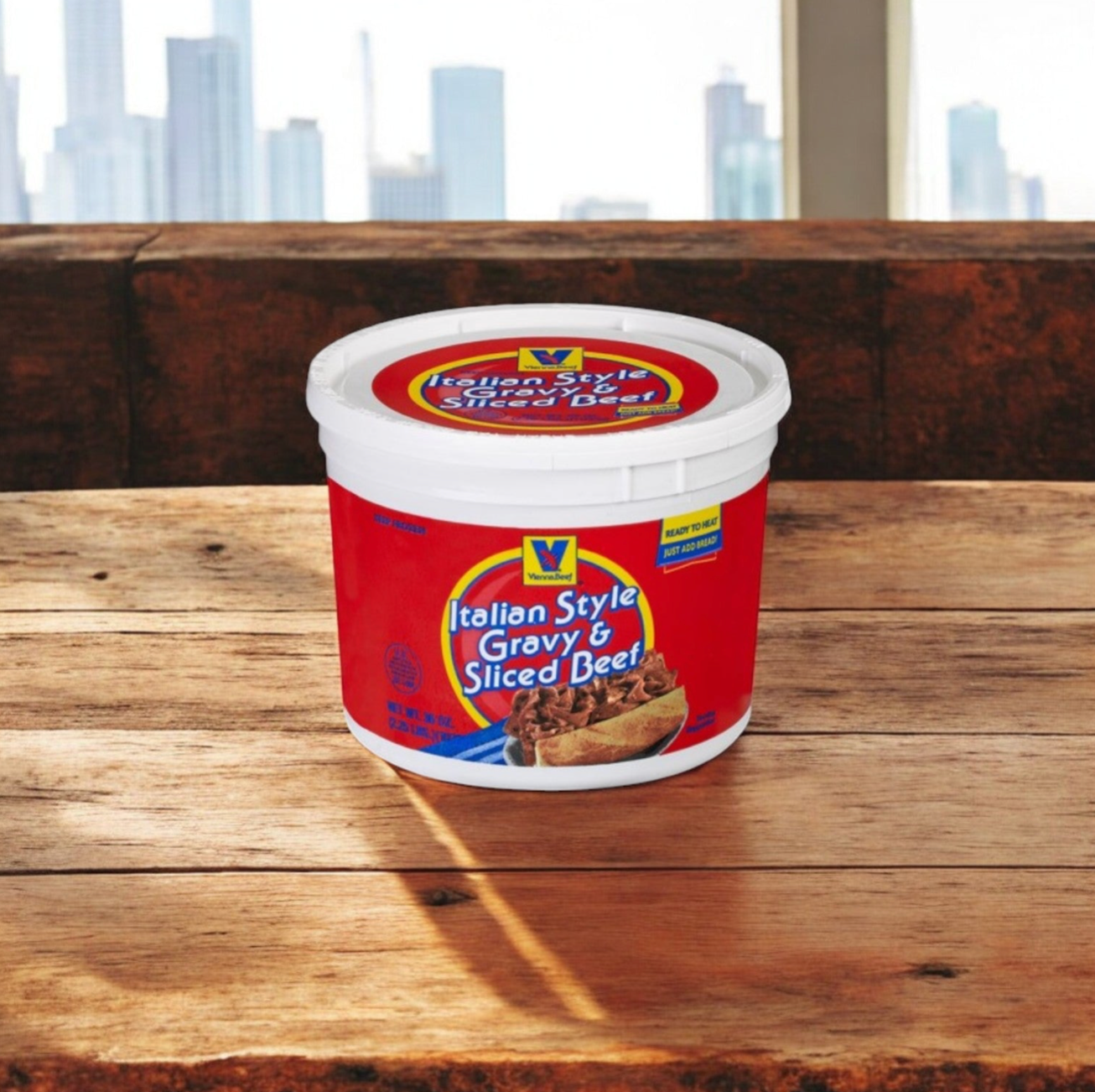 A Chicago’s Best Combo Kit – Lou Malnati’s Deep Dish & Vienna Italian Beef from Lou Malnati's rests on a wooden table, ready to create an authentic Italian beef sandwich, with a city view visible through the window in the background.