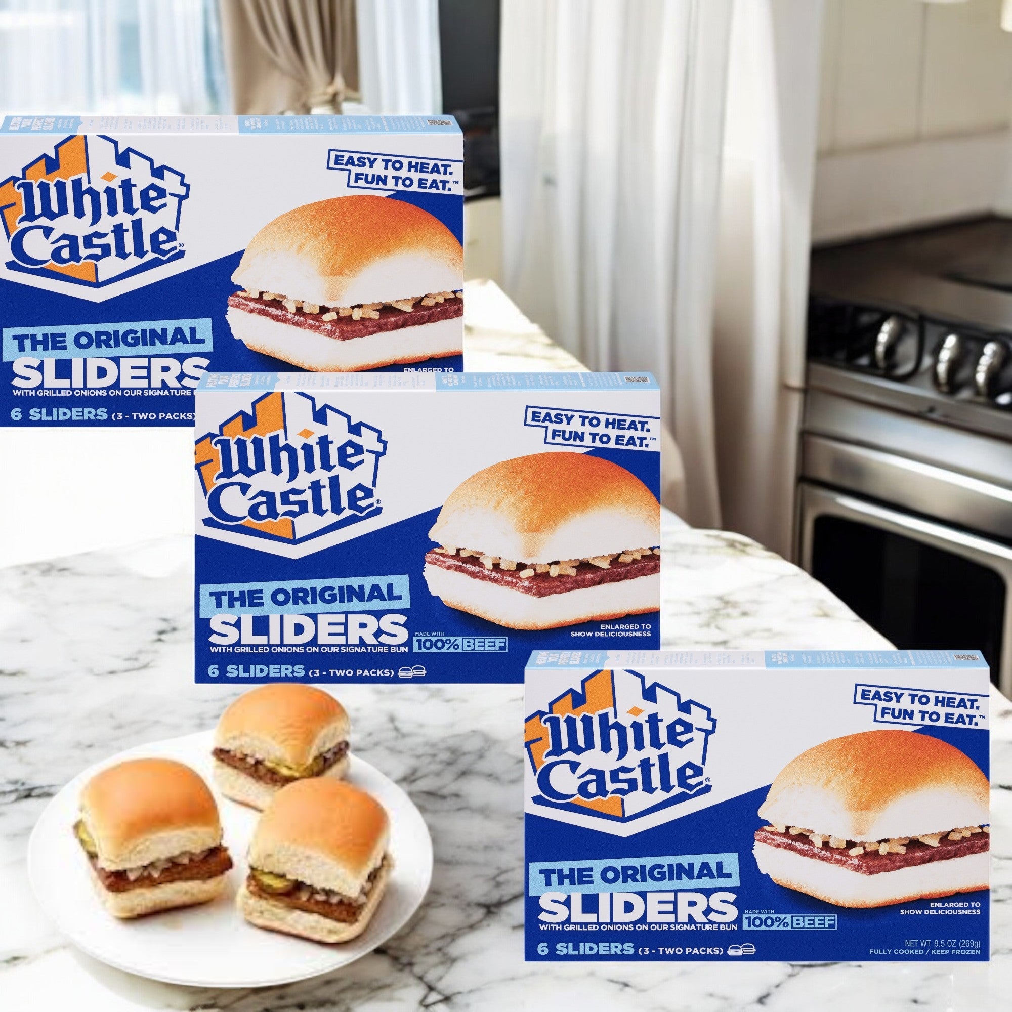 On a marble kitchen counter, three packs of White Castle Microwaveable Hamburgers (each 6 count) sit beside two cooked sliders, showcasing a delicious spread of these frozen mini burgers.