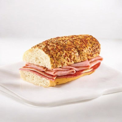 Savor E.A. Sween's Artisan Italian Style Sub with layers of smoked white turkey and provolone cheese on seasoned bread, beautifully presented on a white surface. Ships frozen; shelf life of 30 days once refrigerated.