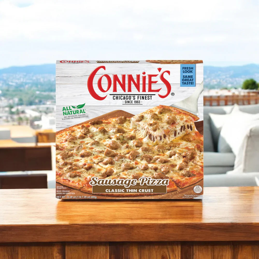 An Easy Lunches Connie's Bundle sits on an outdoor table overlooking a cityscape. With its classic thin crust, this meal invites you to unwind and savor the view.