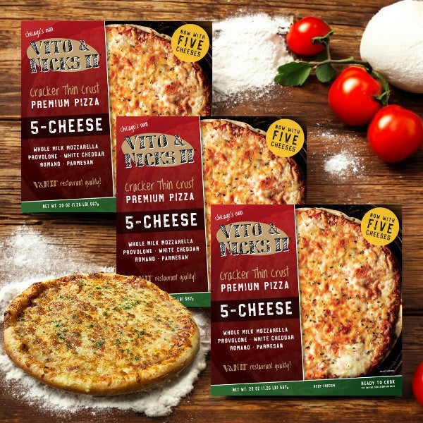Three boxes of Vito & Nick's II Cracker Thin Crust 5-Cheese Pizza, 20 oz., are displayed on a wooden surface alongside a freshly cooked pizza, ripe tomatoes, and basil leaves.