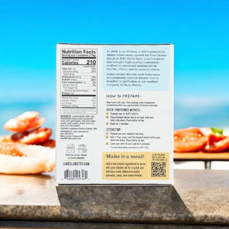 The Luke's Lobster Pre-Split Lobster Tail With Roasted Garlic Butter box displays nutrition facts, preparation instructions, and a QR code. Enjoy an exquisite culinary experience against a blurred outdoor background featuring seafood and blue sky with our Roasted Garlic Butter seasoning.
