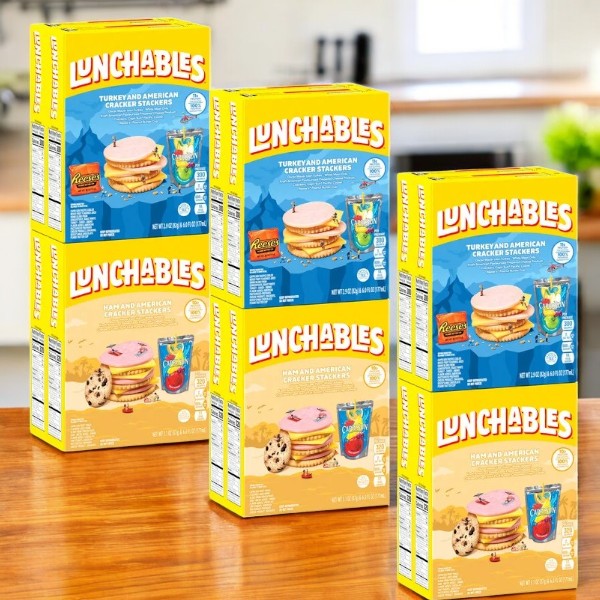 Three packs of Lunchables Cracker Stackers, Ham and Turkey Variety Pack, 4 count each, sit on a wooden table against a kitchen background, ideal for school lunches.