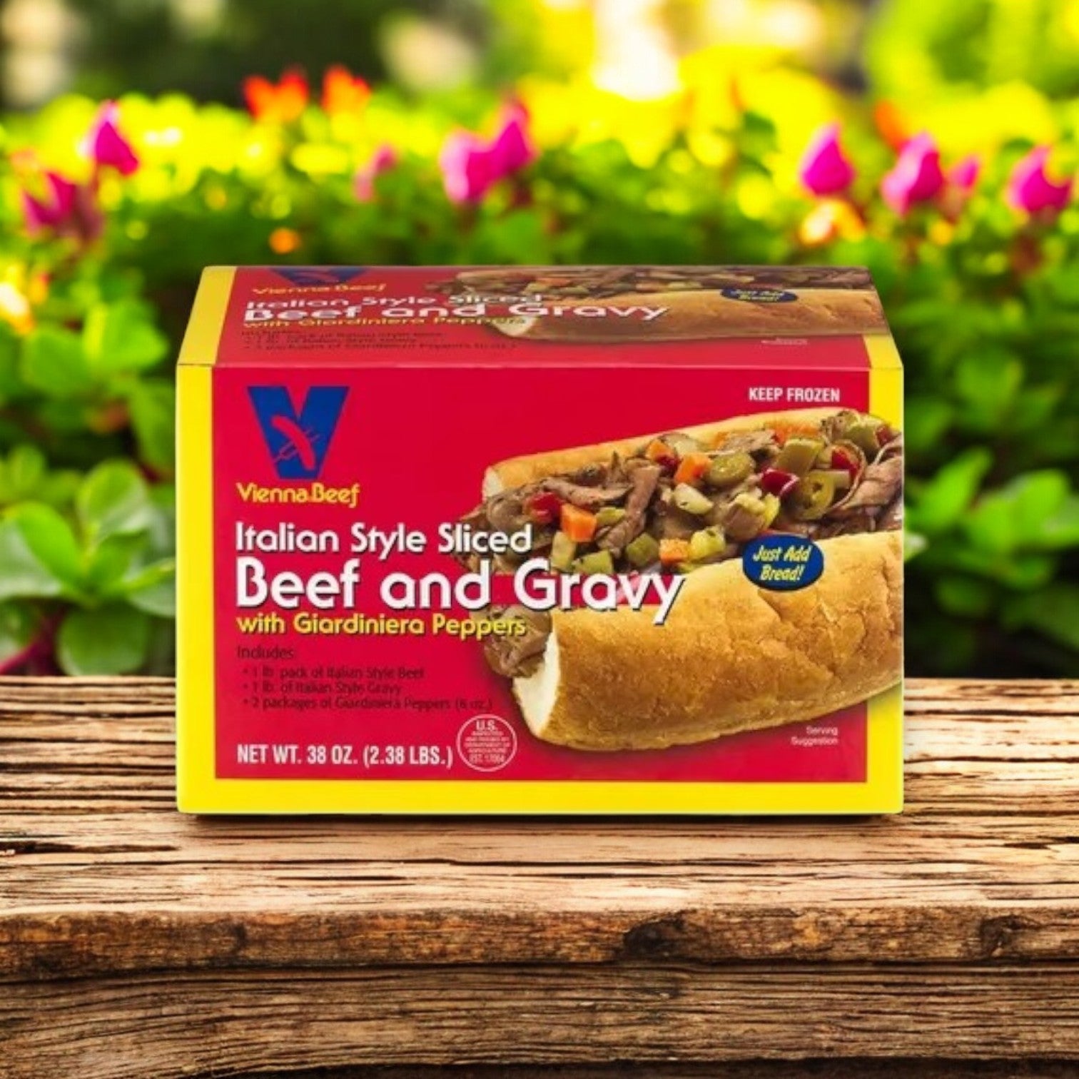 A 38 oz box of Vienna Beef Italian Style Sliced Beef and Gravy with Giardiniera Peppers rests on wood, poised for the ideal Italian beef sandwich, with delicate flowers adding charm.