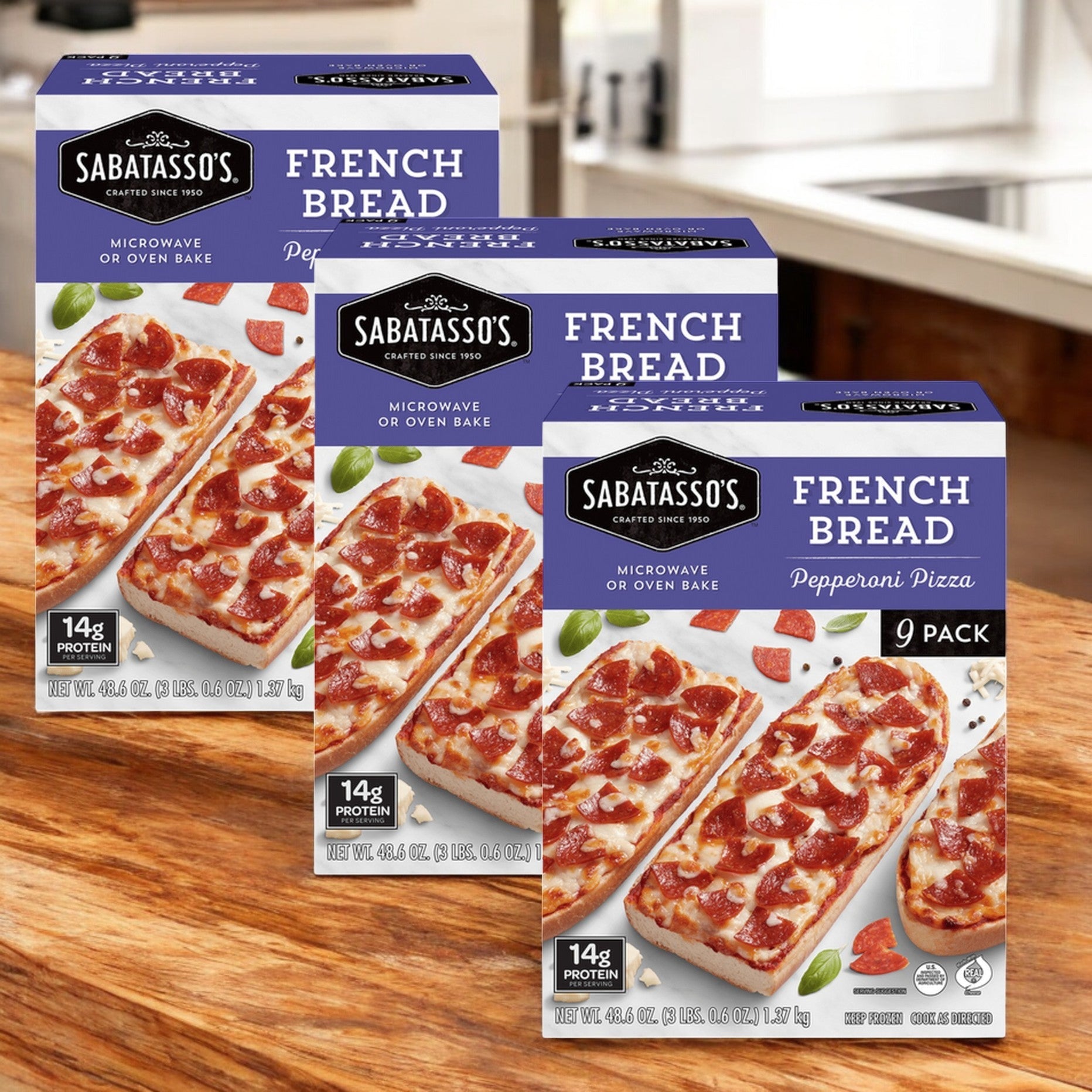 Sabatasso's French Bread Pepperoni Pizza, 48.6 oz., 3 packs, laden with mozzarella cheese, are stacked on a wooden surface.
