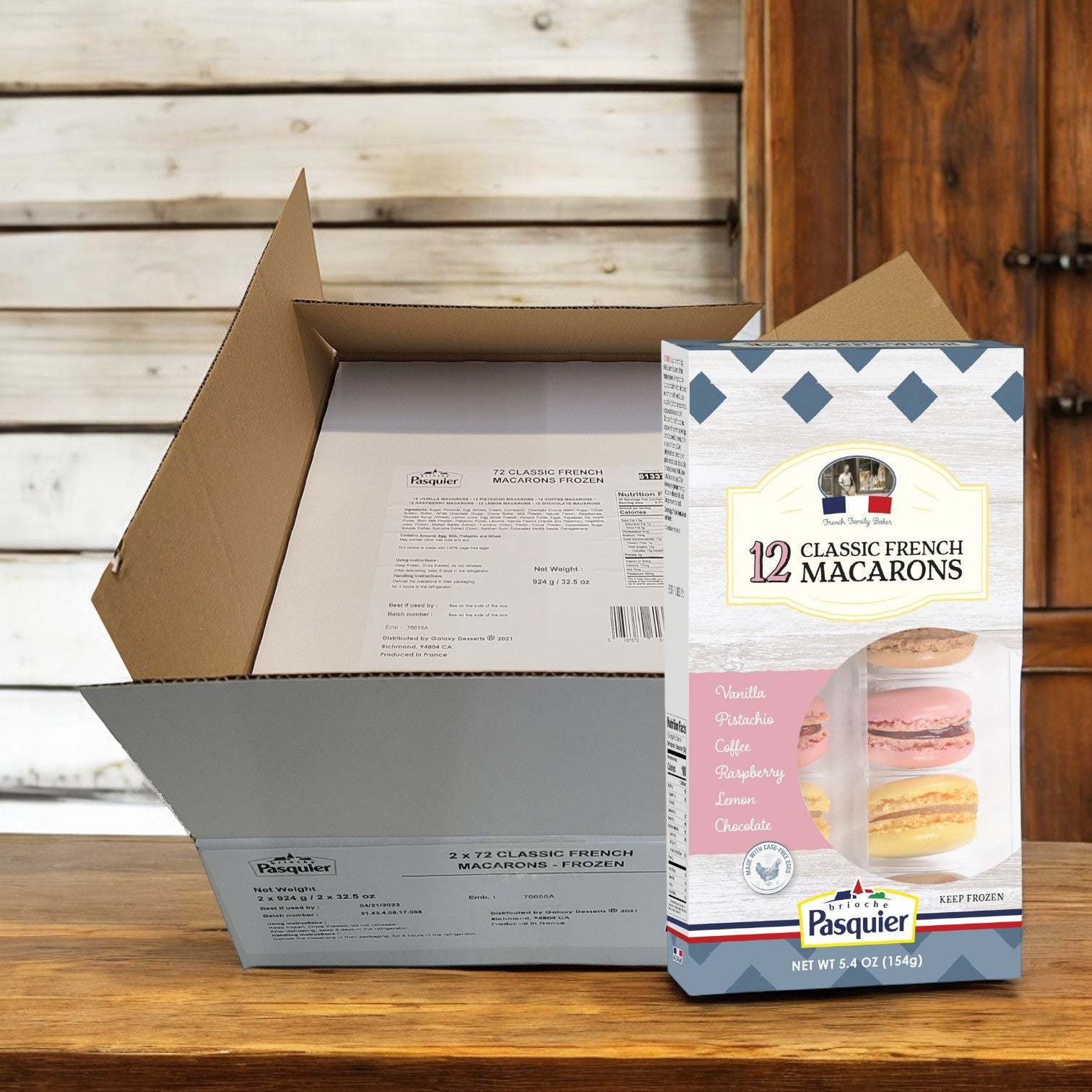 An open cardboard box on a wooden table reveals Pasquier's Classic French Macaron cookies—a luxury dessert featuring 144 macarons per case in flavors such as vanilla, pistachio, coffee, raspberry, lemon, and chocolate.