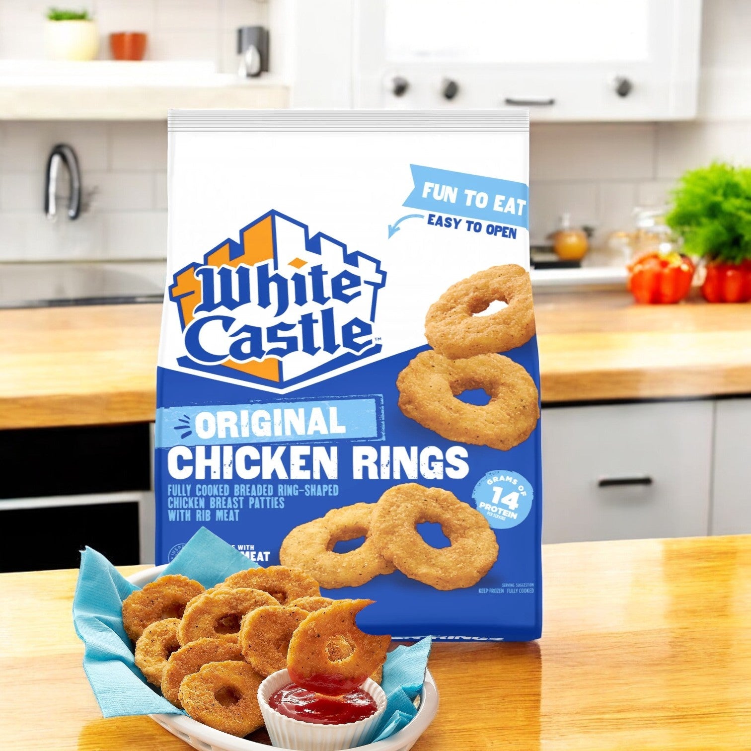 A 20oz bag of White Castle Original Chicken Rings sits on a kitchen counter next to a plate of these tasty frozen snacks, ideally paired with dipping sauce.