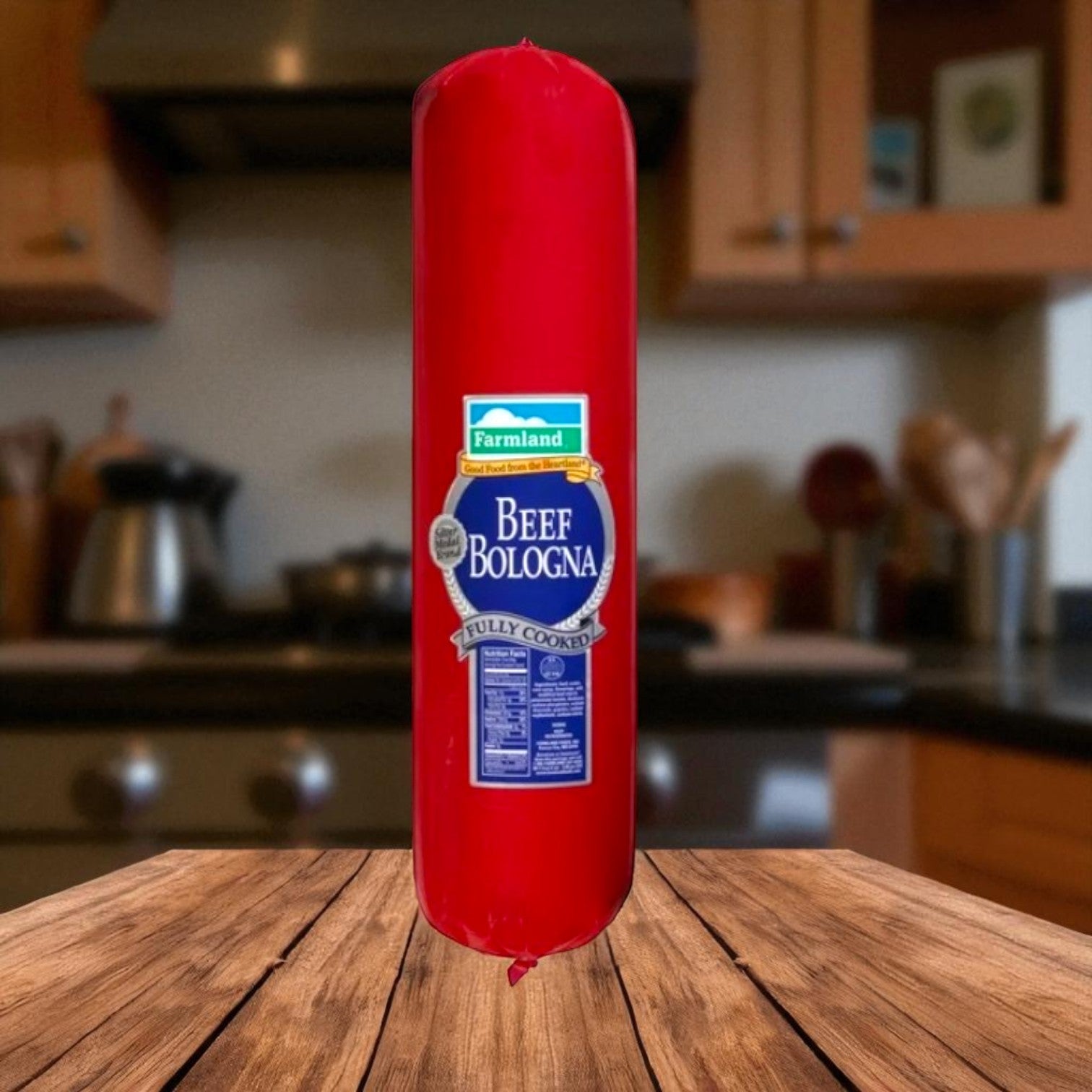 A 10-pound bulk roll of Farmland Silver Medal Beef Bologna by Endless Market in red packaging stands upright on a wooden table in a kitchen setting.