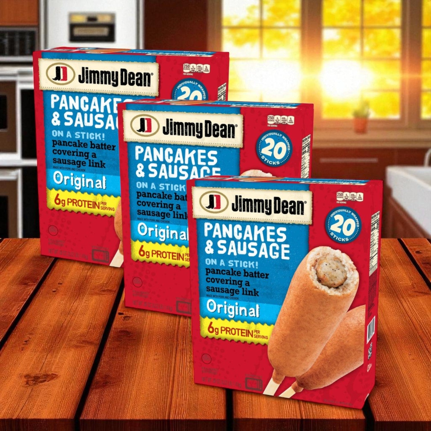 Three packs of Jimmy Dean Original Pancake and Sausage on a Stick, Frozen 20 ct, are set out on a wooden table in a sunlit kitchen, ideal for a quick breakfast.